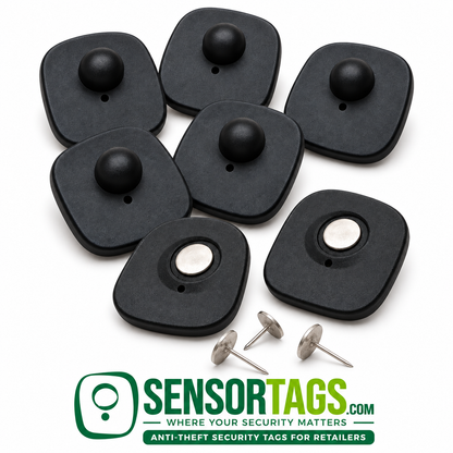 Black mini security tags showing domed fronts, reverse sides with fitted pins, and three loose silver pins on white.