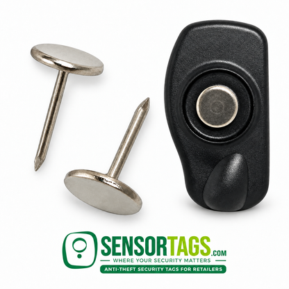 Flat silver security pin seated in a black pencil tag, with two loose smooth pins alongside on a white background.